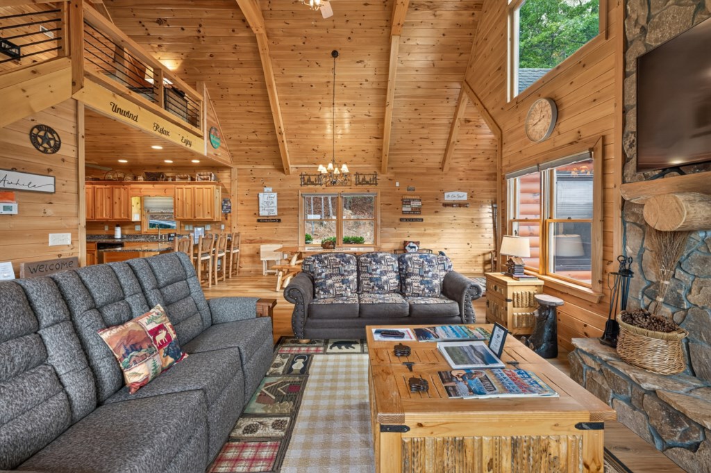 Rustic living room with vaulted ceilings and cozy seating by a stone fireplace.