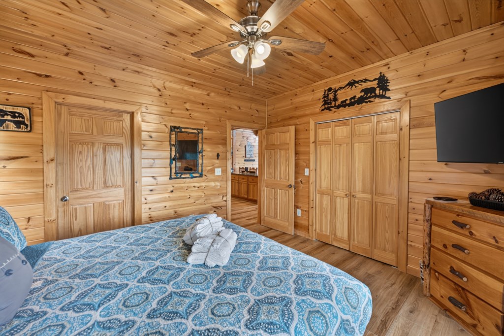 Cozy cabin bedroom with rustic wood paneling and a plush king-size bed.