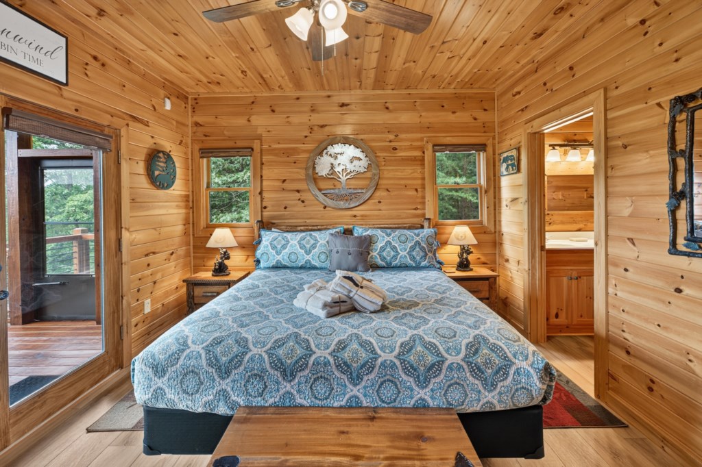 Cozy cabin bedroom with rustic wood paneling and private balcony access.