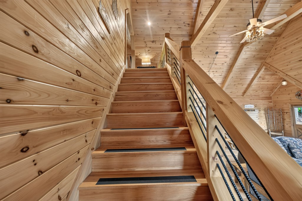 Rustic wooden staircase leading to a cozy loft area with warm lighting.