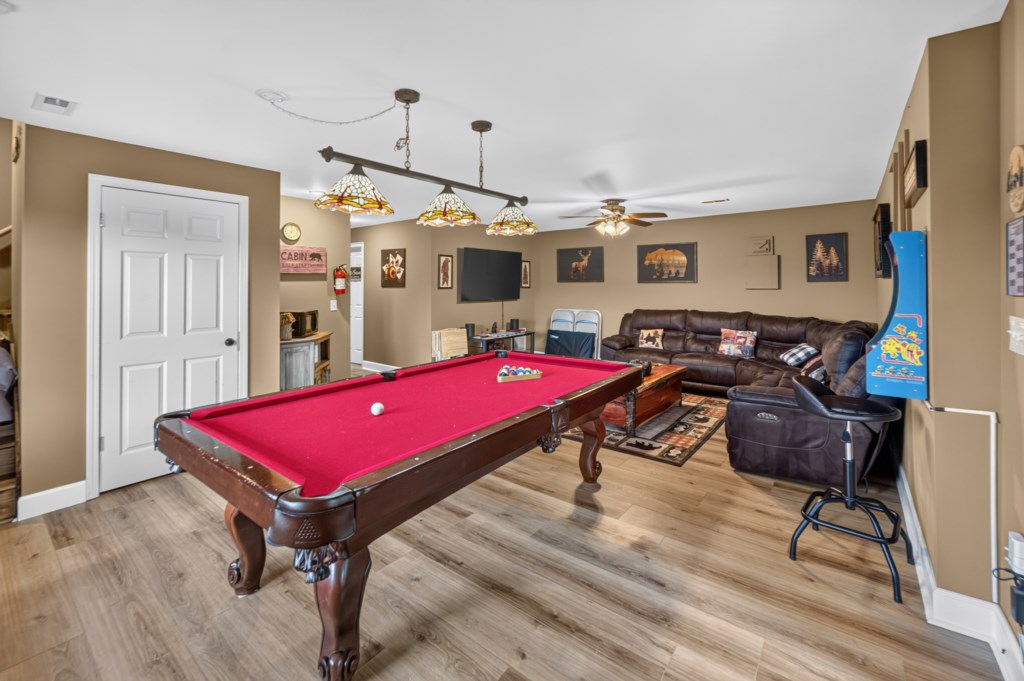 Cozy game room with pool table, arcade machine, and comfy seating for entertainment.