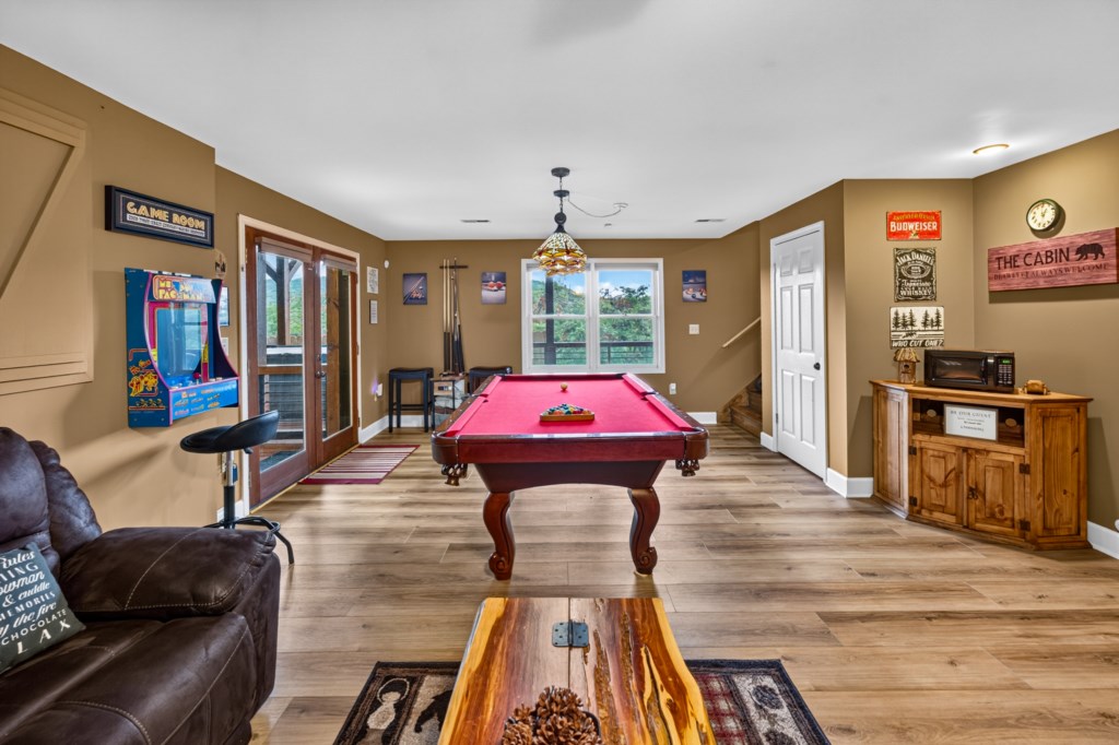 Fun game room with pool table and arcade machine for entertainment.