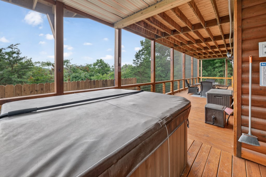 Relax in the covered hot tub with serene forest views on the spacious deck.