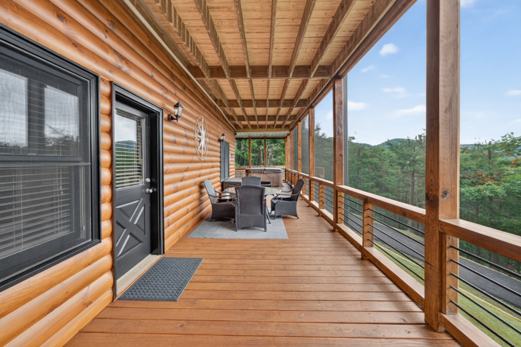 Spacious covered deck with seating and stunning forest views.