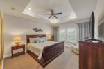 Large primary bedroom with tray ceilings and plush padded carpets 