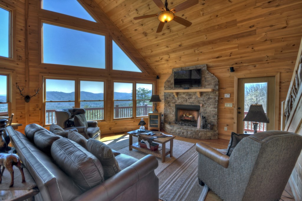Main level living room with floor to ceiling windows and seasonal gas log fireplace 