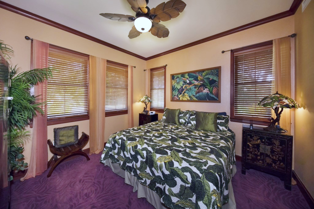 Sleep soundly in this tropical king bedroom with leafy bedding, wood trim, and soft ambient lighting.
