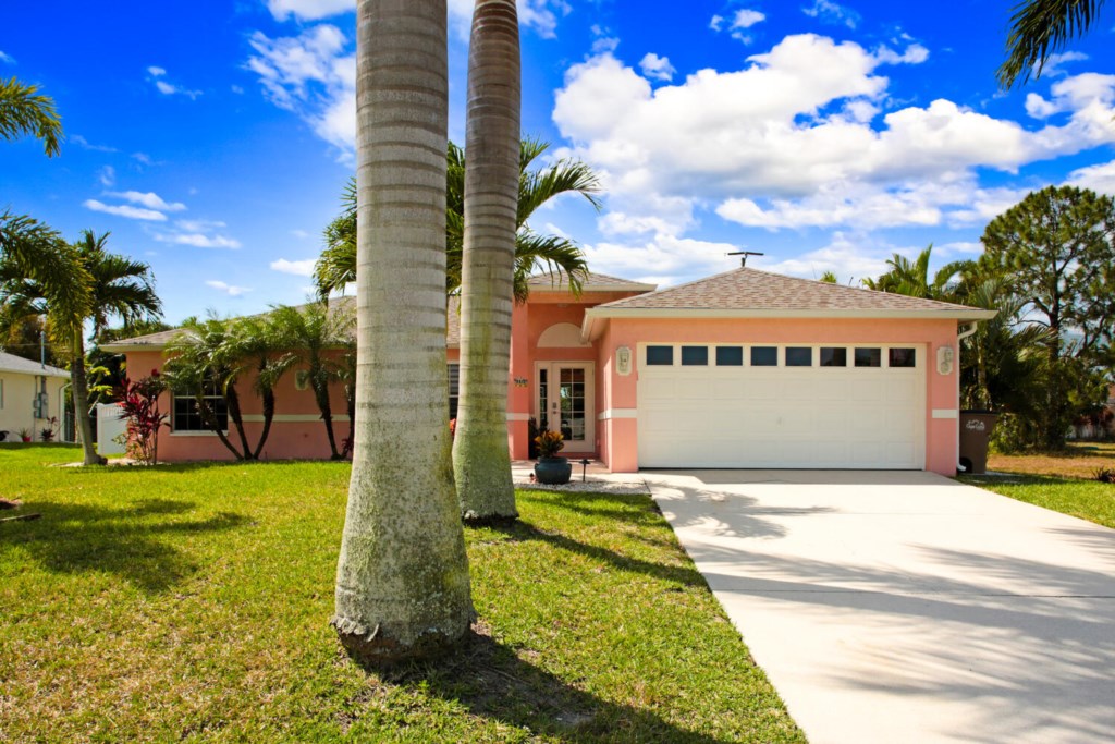 Charming home with tropical landscaping and spacious driveway.