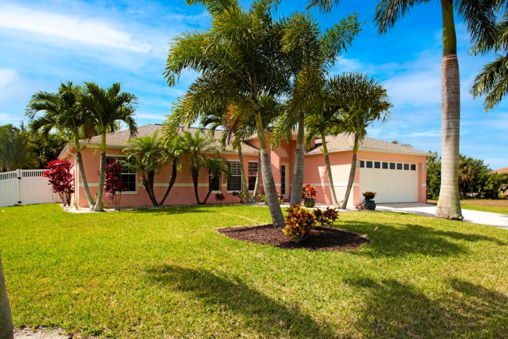 Charming tropical home with lush landscaping and a spacious front yard.