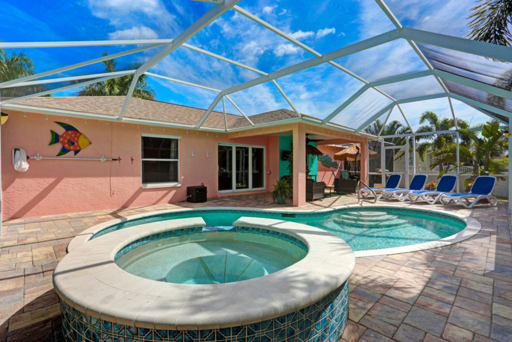 Relax by the private pool with spa under a screened enclosure, perfect for sunny days.