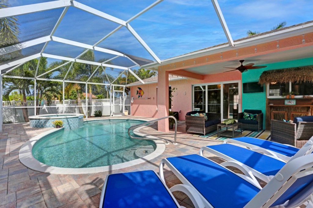 Screened pool area with spa and tiki vibes, perfect for relaxing and entertaining.