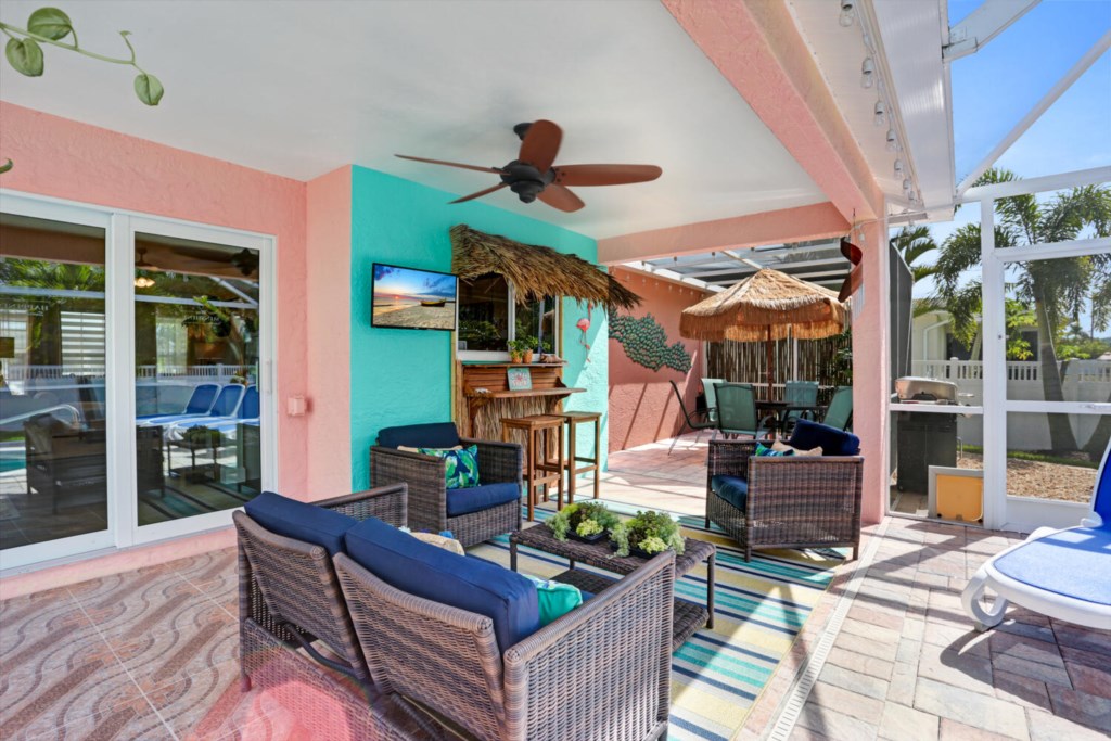 Tropical-themed patio with cozy seating and a tiki bar, perfect for relaxing by the pool.