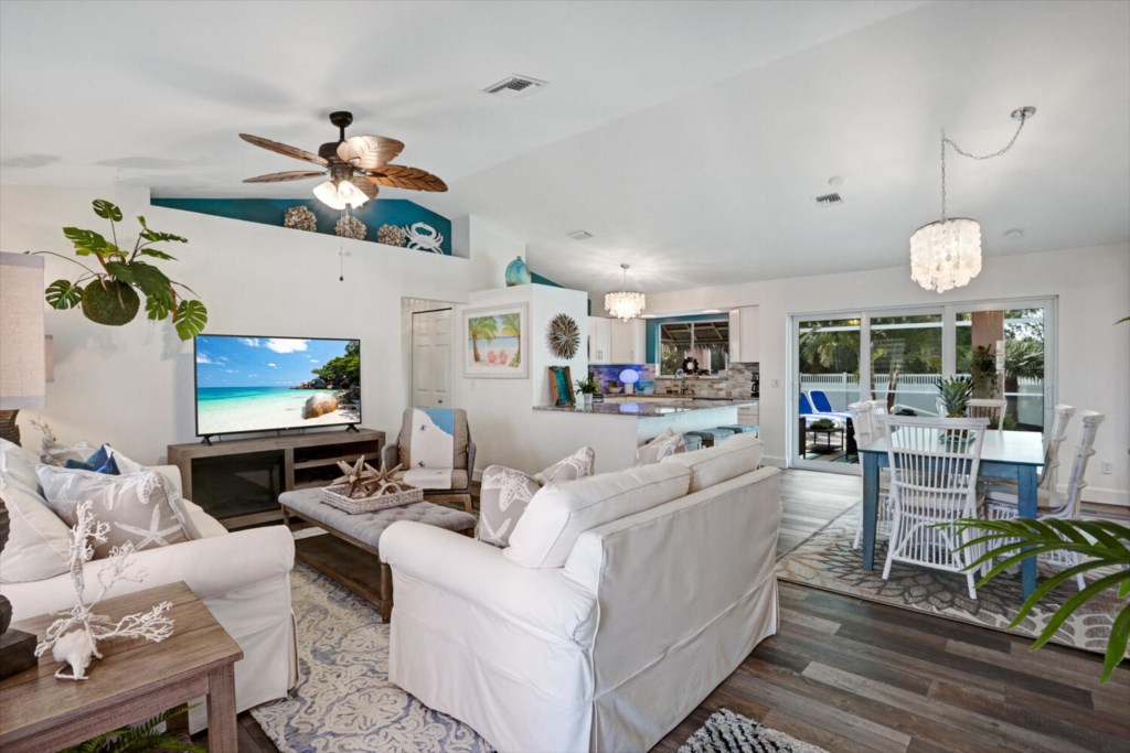 Open-concept living area with cozy seating, large TV, and access to a sunlit patio.