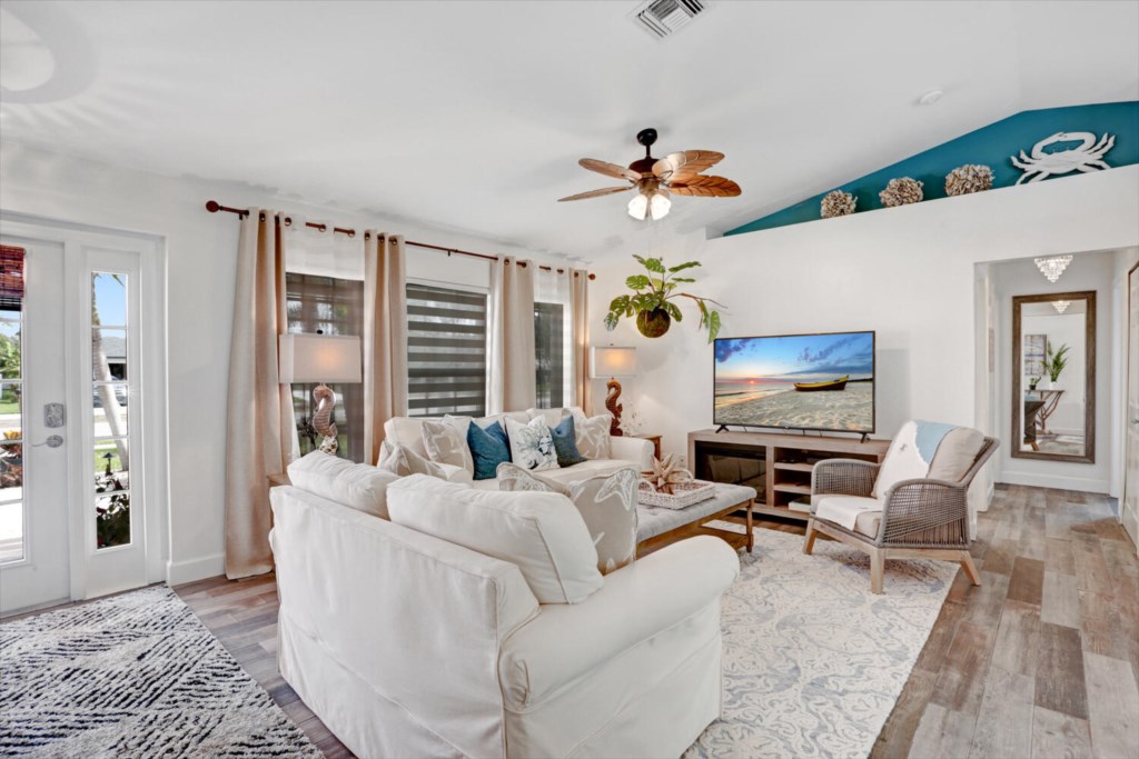 Bright living room with cozy seating and large TV, perfect for relaxing evenings.