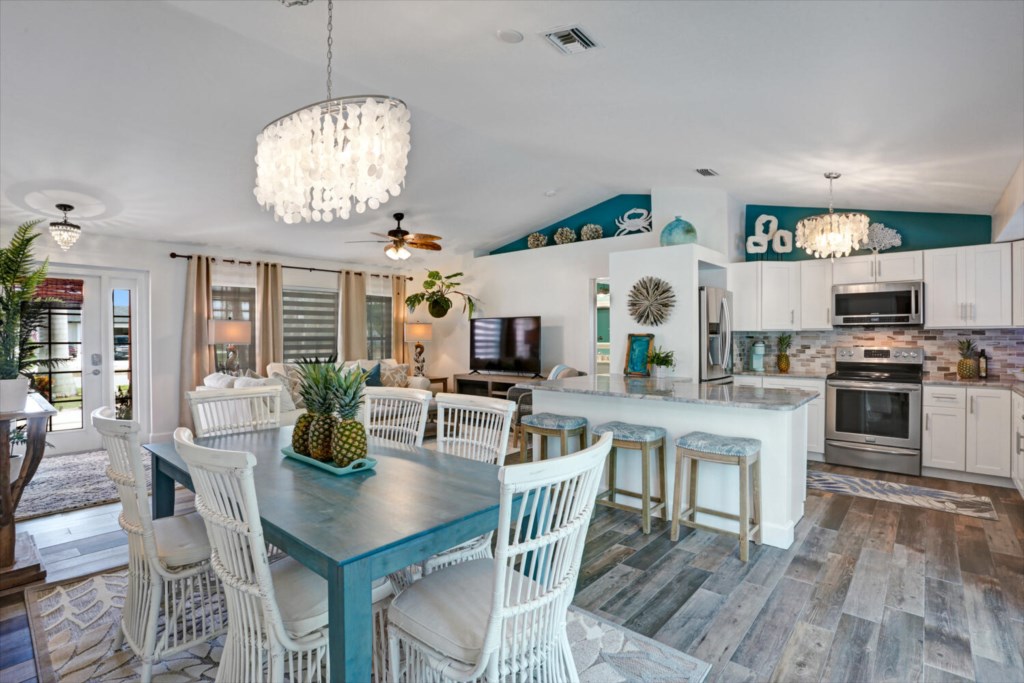 Open-concept kitchen and dining area with modern appliances and elegant lighting.