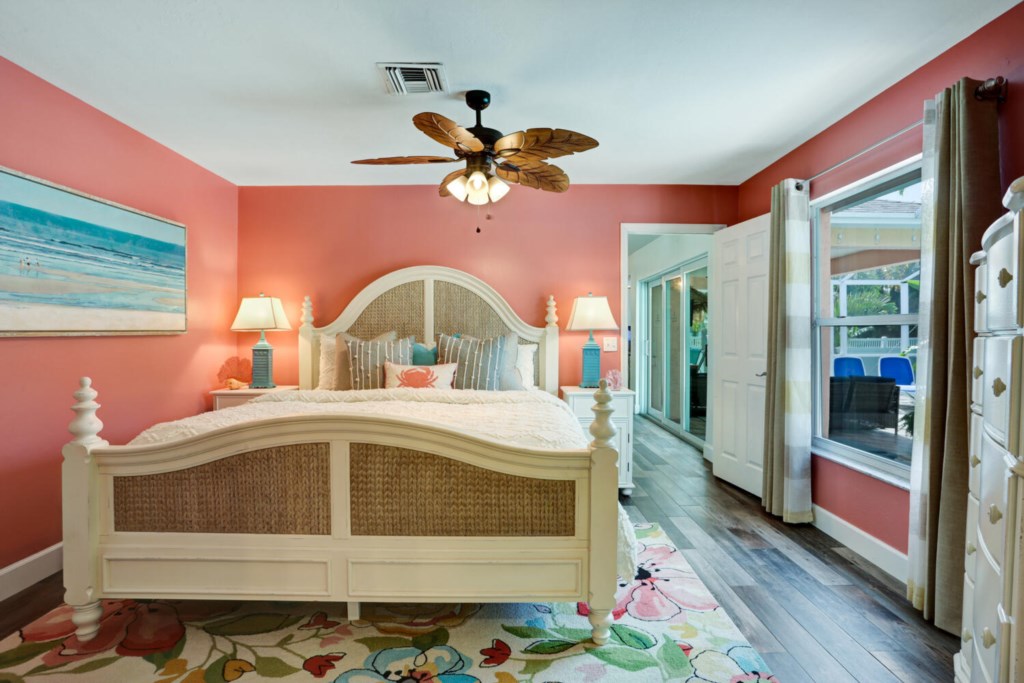 Master bedroom with tropical decor, TV, ensuite, and pool views