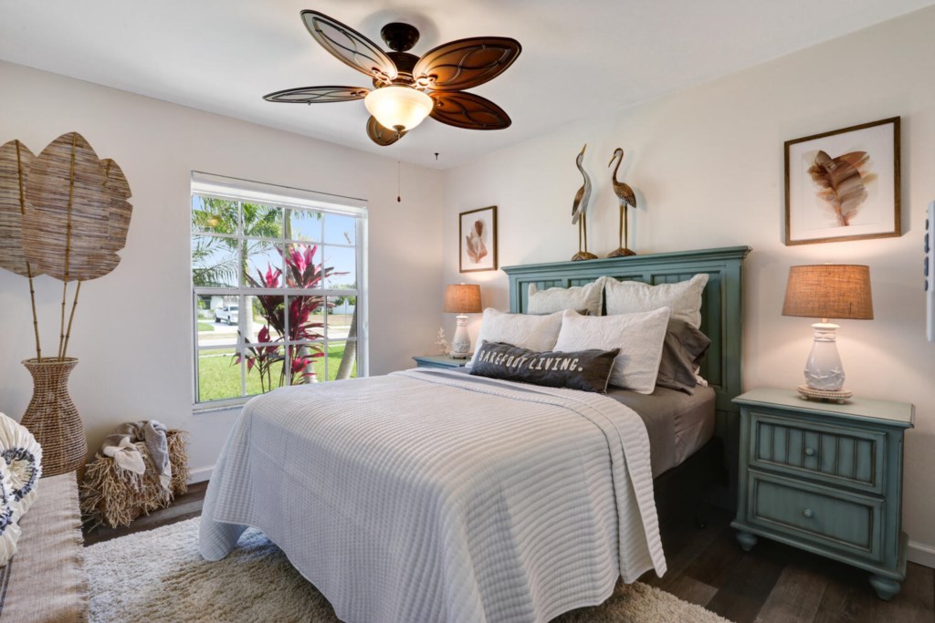 Charming bedroom with coastal decor and garden views, perfect for a relaxing retreat.