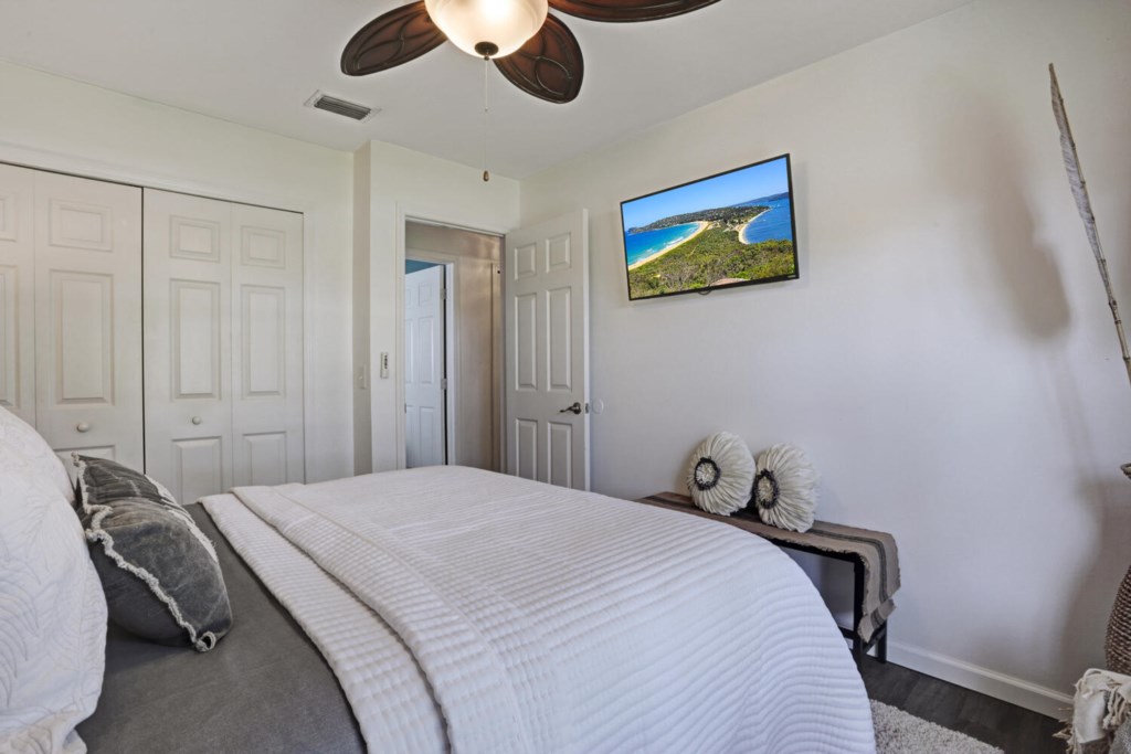 Cozy bedroom with a ceiling fan and wall-mounted TV for relaxing evenings.