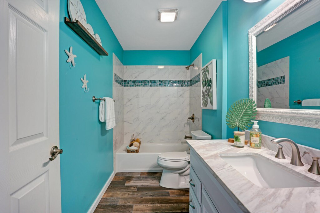 Bright bathroom with turquoise walls, marble vanity, and relaxing bathtub.