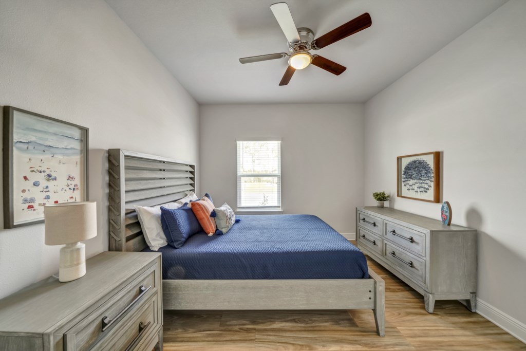 Guest room featuring a queen bed with ceiling fan and flat screen television 