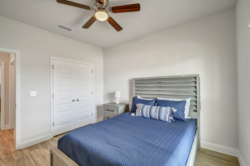 Additional queen guest bedroom with ceiling fan and flat screen television