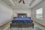 Stunning primary bedroom with decorative tray ceiling, flat screen television, ceiling fan, and attached bath