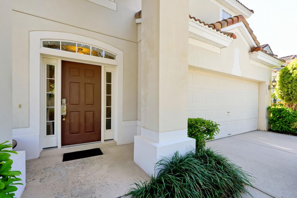 Inviting front entrance with a spacious driveway and lush greenery.