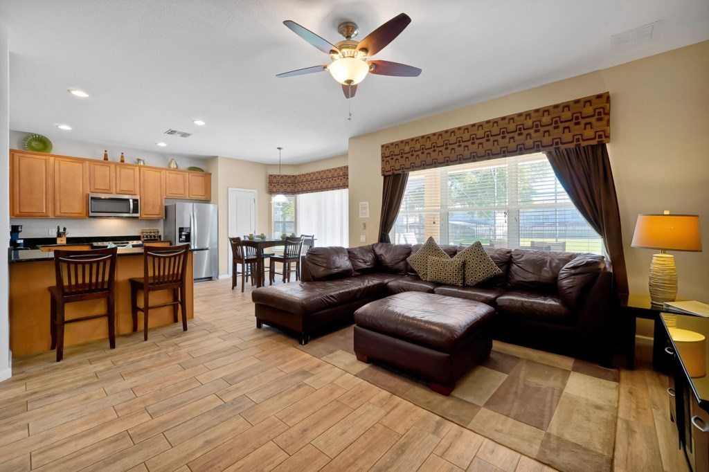 Open-plan living area with a cozy leather sectional and modern kitchen, perfect for relaxing and dining.