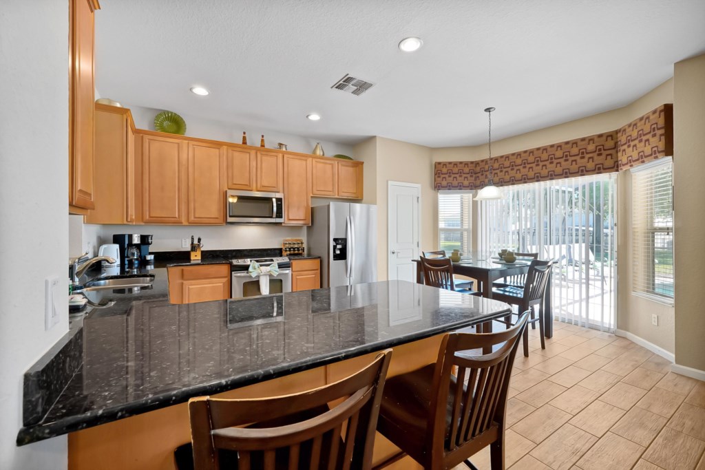 Modern kitchen with granite countertops and dining area overlooking the pool.