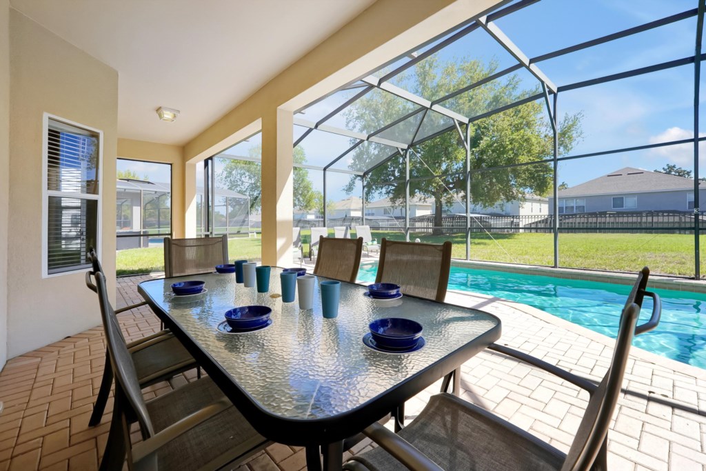 Screened patio with dining table overlooking private pool, perfect for outdoor meals and relaxation.
