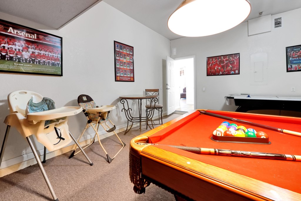 Family-friendly game room with pool table, high chairs, and sports decor.
