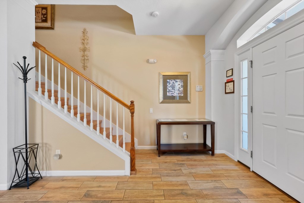 Welcoming foyer with elegant staircase and convenient coat rack.