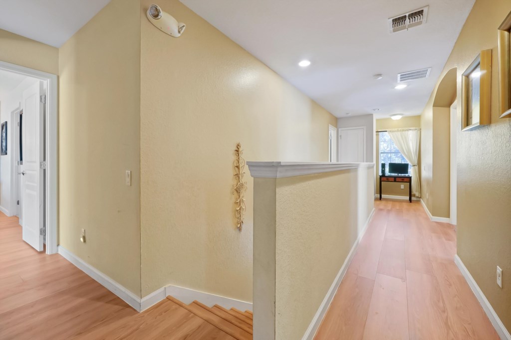 Spacious hallway with warm lighting and wood floors, leading to cozy rooms.