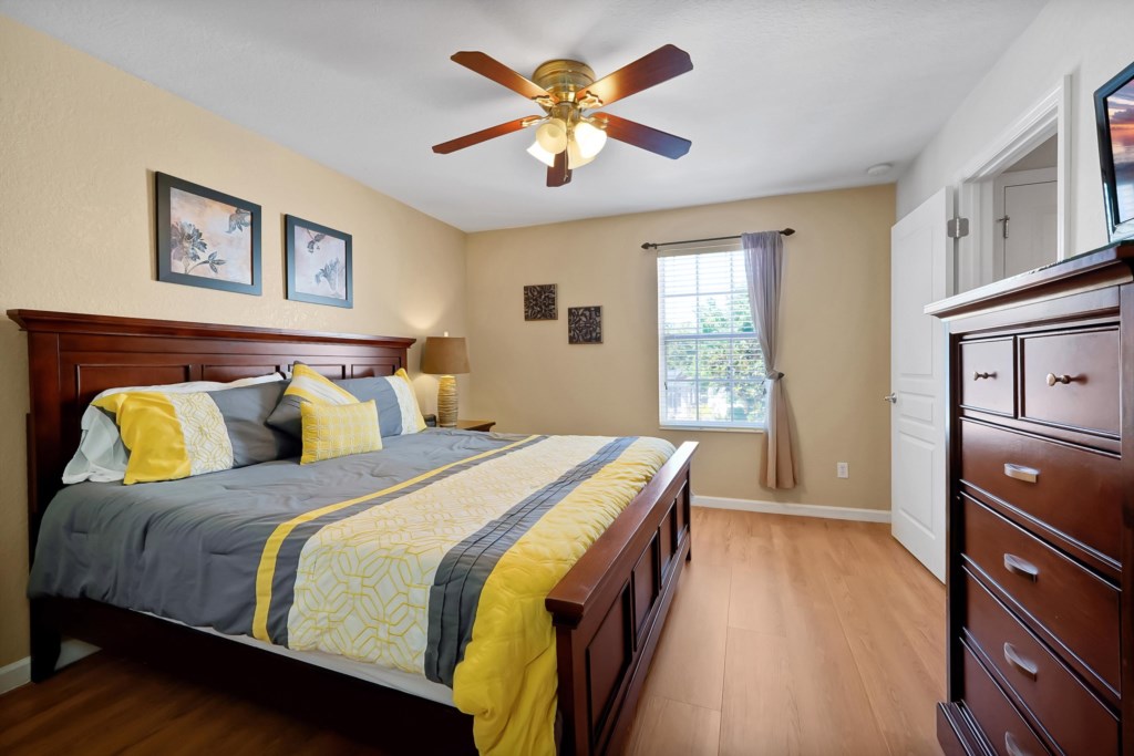 Cozy bedroom with a king-size bed, ceiling fan, and natural light.