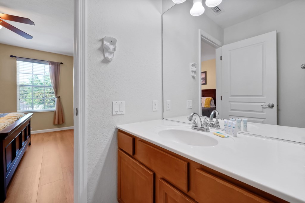 Modern bathroom with large mirror and ample counter space, connected to a cozy bedroom.