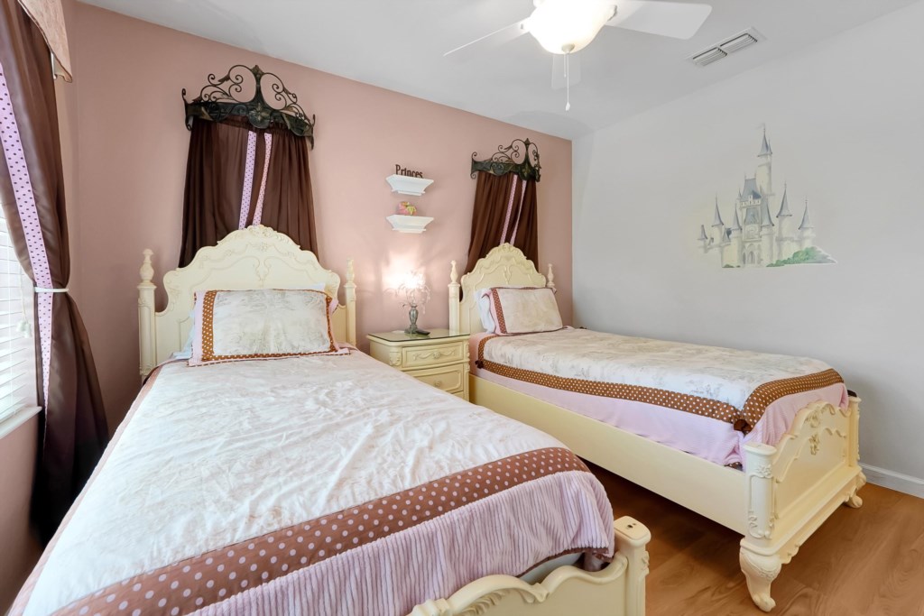 Charming princess-themed bedroom with twin beds and whimsical castle mural.
