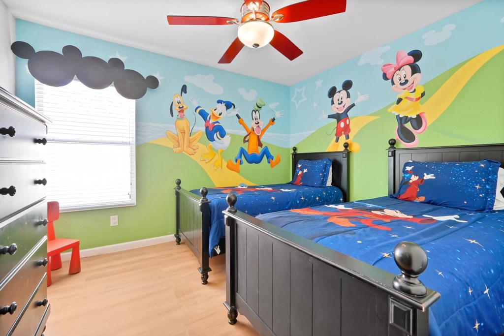 Fun-themed kids' bedroom with vibrant mural and twin beds for a magical stay.