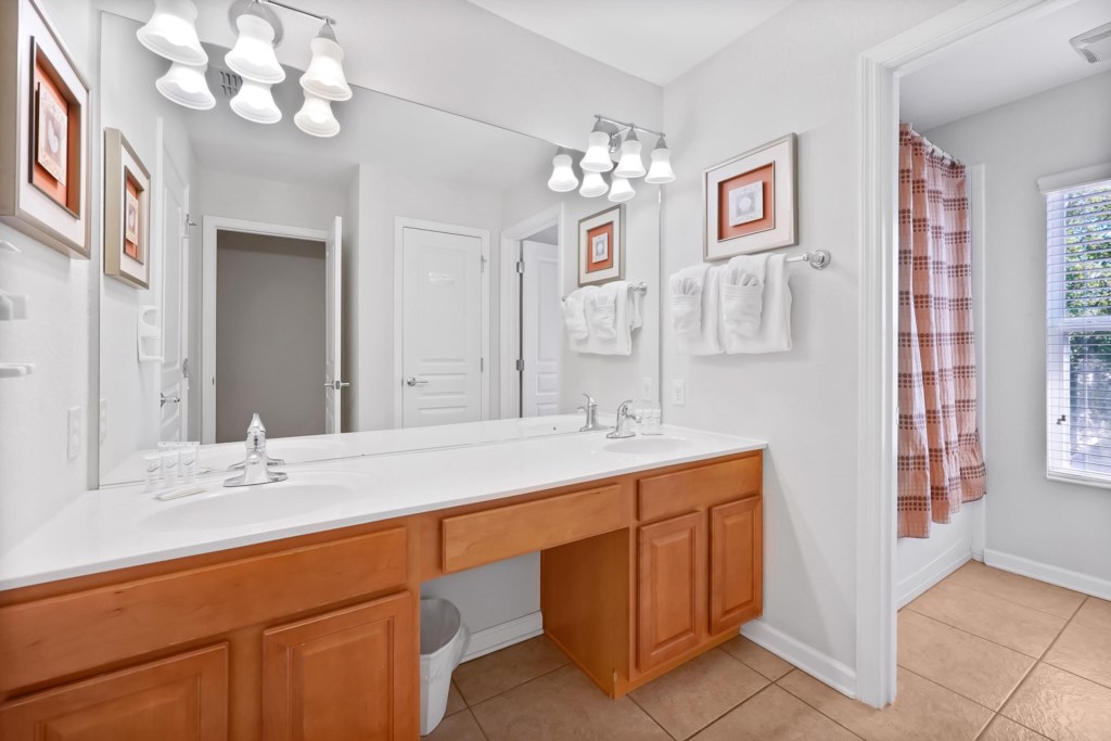 Bright bathroom with double sinks and a shower-tub combo for convenience.