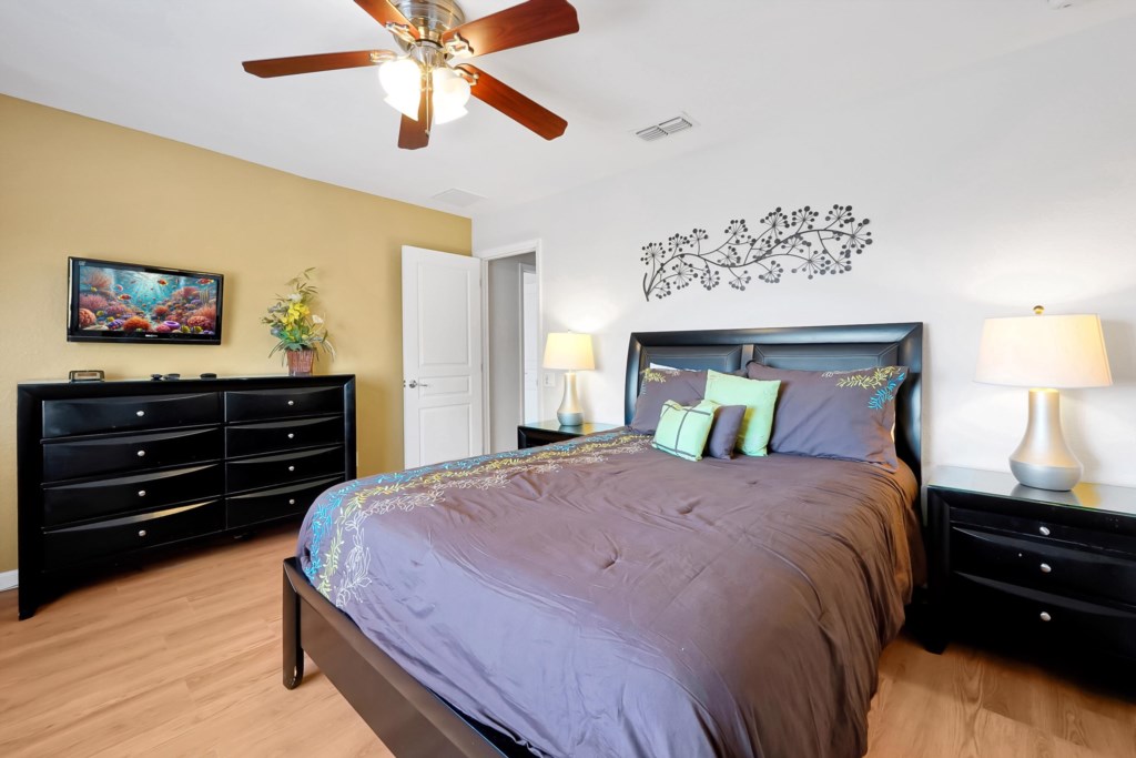 Cozy bedroom with a plush bed, modern decor, and a flat-screen TV for relaxing evenings.