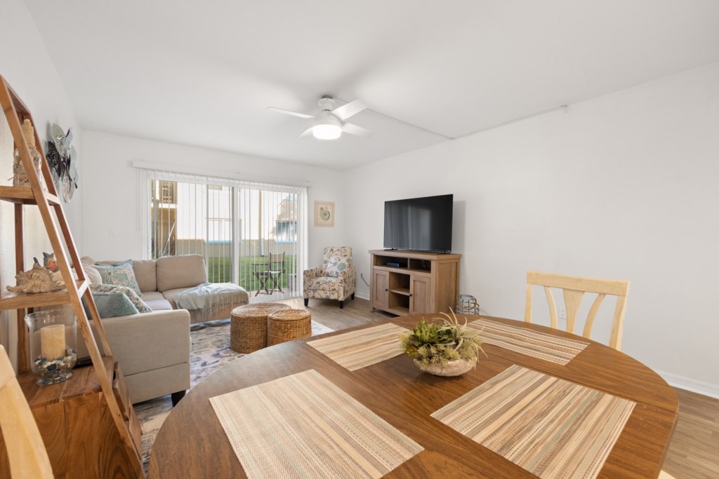 Bright living room with dining area, comfy seating, and a large TV.