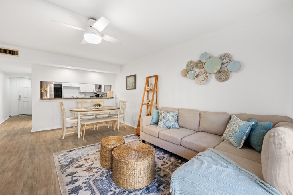 Bright, open-plan living area with comfy seating and adjacent modern kitchen.