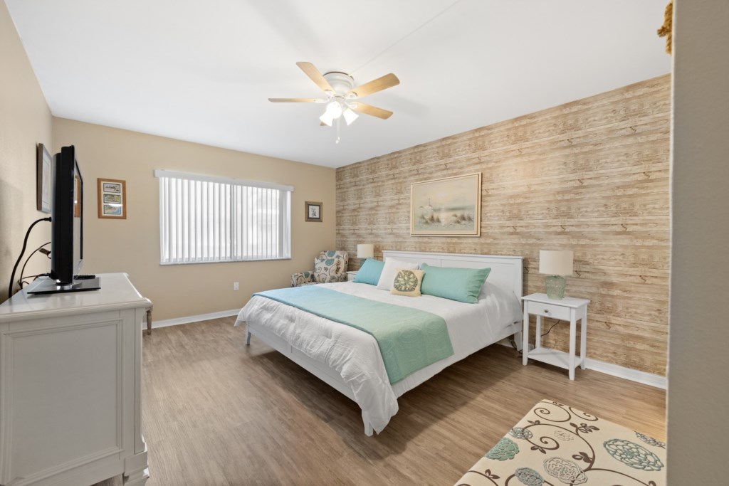 Serene bedroom with a king-size bed, rustic accent wall, and modern amenities.