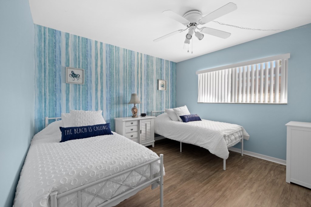 Beach-themed twin bedroom with vibrant blue decor, ideal for relaxing.