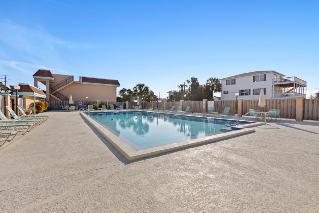 Sunny pool area with ample seating, perfect for relaxing or sunbathing.