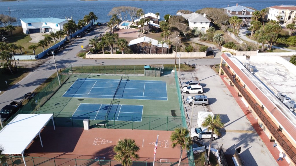 Aerial view of tennis courts next to the beach, ready for an active vacation.