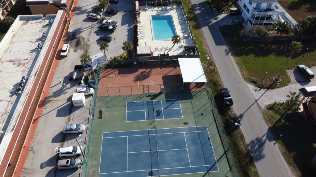 Aerial view of on-site amenities including a pool, tennis, and basketball courts.