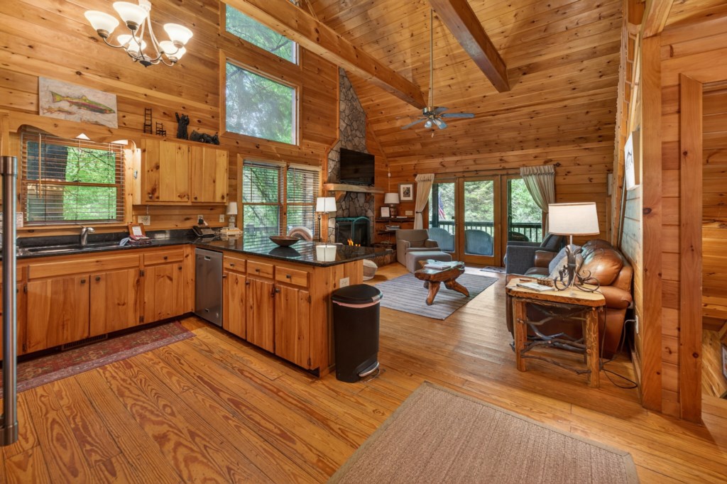Rustic open-concept kitchen and living area with vaulted ceilings and forest views.