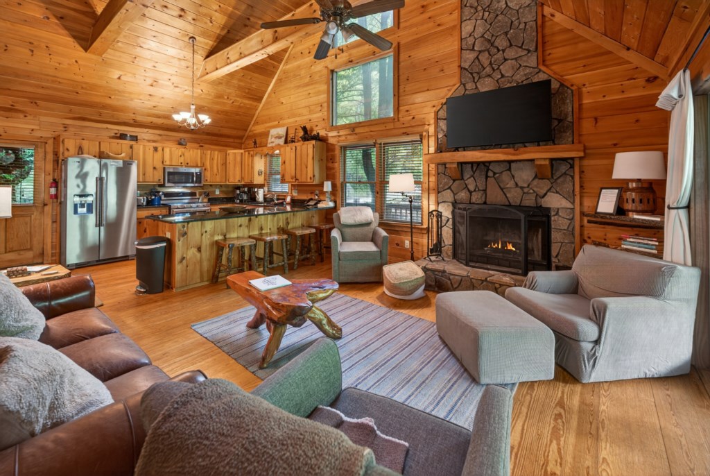 Rustic open-concept living area with cozy fireplace and modern kitchen amenities.