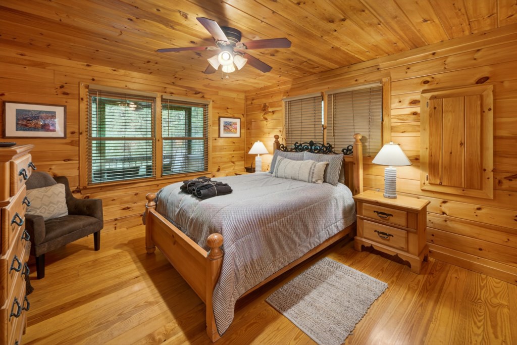 Rustic bedroom with wood paneling and a cozy queen bed, perfect for a peaceful retreat.