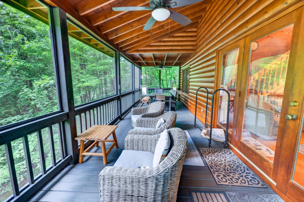 Cozy screened porch with wicker seating and lush forest views.